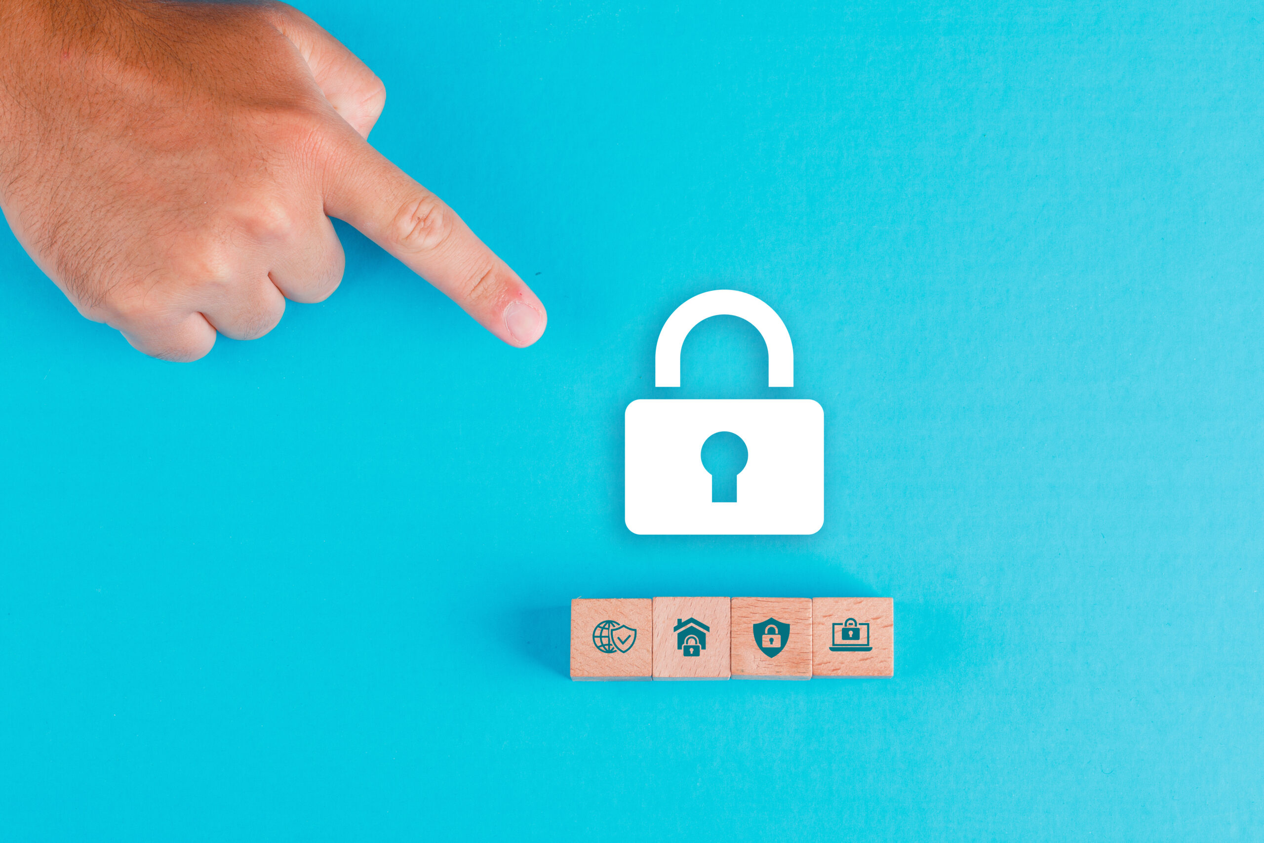 Security concept with wooden blocks, paper lock icon on blue background flat lay. man hand pointing. horizontal image
